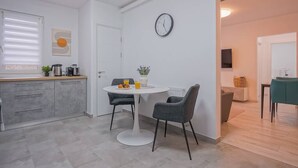 A modern kitchen with a dining area, featuring a white table, two chairs, and a clock on the wall. - Mountain Hideaway w. Netflix and Mountain View (Brașov)