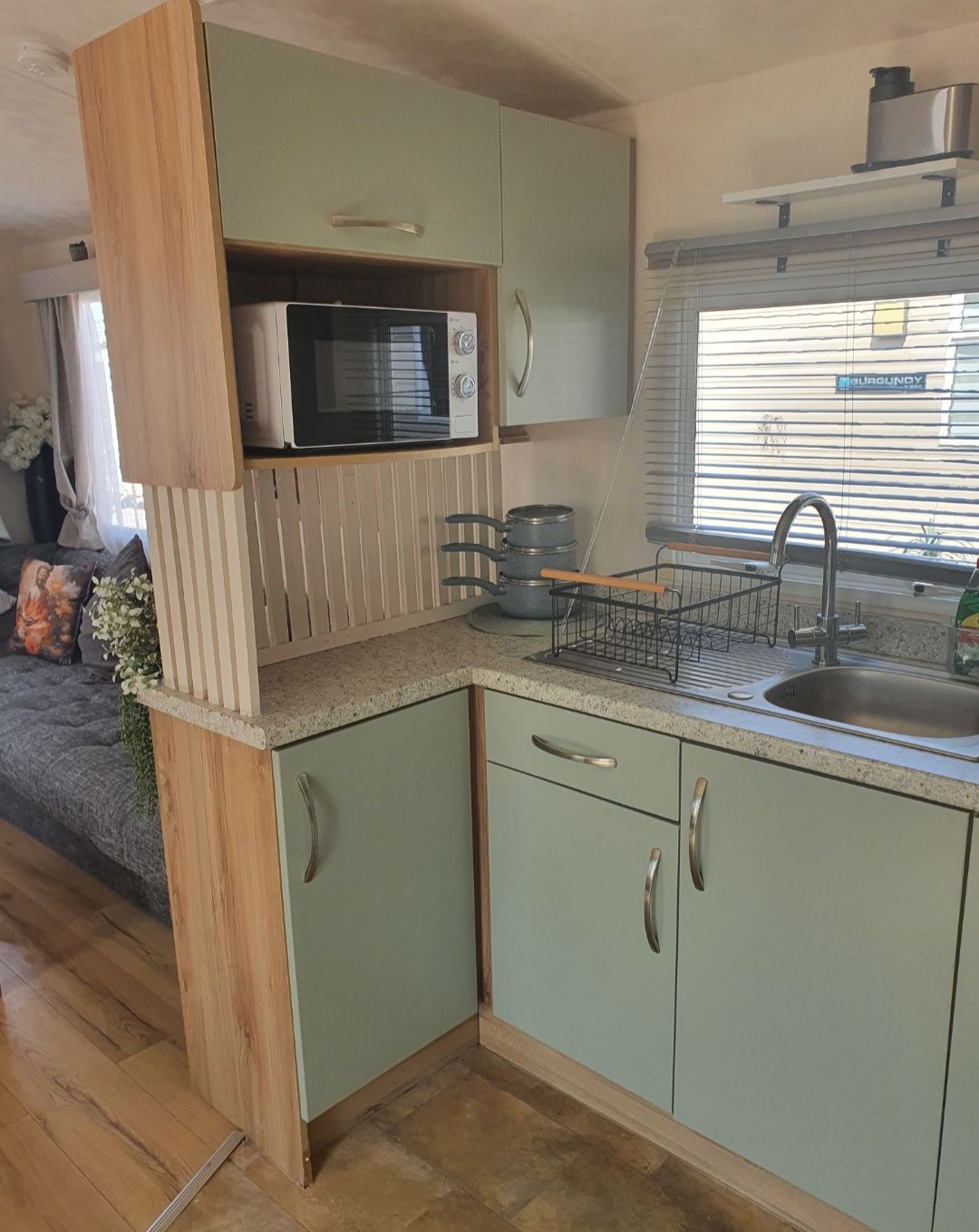 A compact kitchen with a microwave, sink, and wooden cabinets.