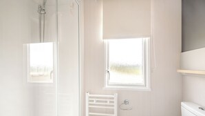 Un baño con ducha, inodoro, toallero y ventana.