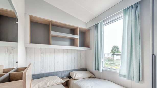 Una habitación con literas, un escritorio y un ventanal con cortinas.