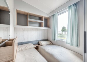 Ein Zimmer mit einem Etagenbett, einem Schreibtisch und einem Fenster mit Vorhängen.