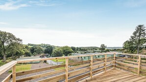 Une terrasse en bois offrant une vue sur un quartier résidentiel, avec des maisons et une route.