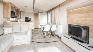 Una sala de estar moderna con un sofá, televisor y un comedor con sillas y mesa.