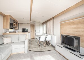 Ein modernes Wohnzimmer mit einer Couch, einem Fernseher und einem Essbereich mit Stühlen und einem Tisch.