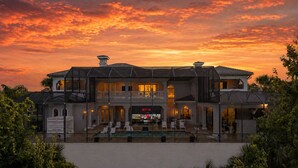 A large, two-story house with a balcony, a pool, and a sign for Netflix. - Mansion at Reunion | 11BR Luxe Stay w/ Private Pool, Theater, Arcade, and Themed Rooms near Disney (Kissimmee)