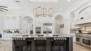 A spacious kitchen with a large island, white cabinetry, and modern appliances. - Mansion at Reunion | 11BR Luxe Stay w/ Private Pool, Theater, Arcade, and Themed Rooms near Disney (Kissimmee)