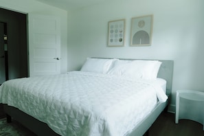 A bedroom with a bed, a door, and two wall-mounted artworks.