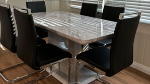 Une salle de conférence avec une table en marbre, des chaises noires et une grande fenêtre équipée de stores.