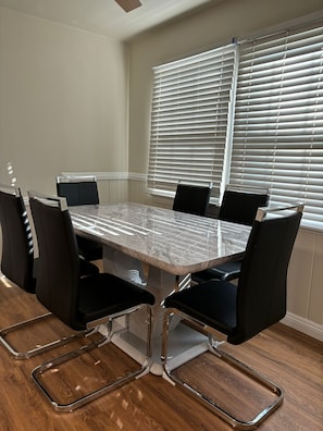 A conference room with a marble table, black chairs, and a large window with blinds.