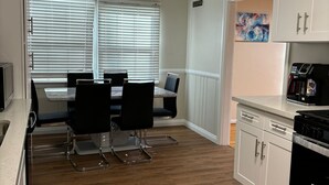 Une cuisine moderne avec des meubles blancs, une cuisinière noire et un coin repas comprenant deux chaises et une table.