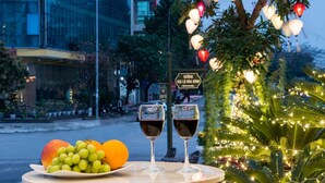 A table with a plate of fruit and two wine glasses, set outdoors with a street view in the background. - Móng Cái Place (Mong Cai)