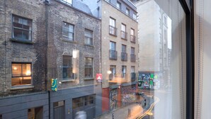A street view with buildings, a visible storefront with a sign, and a pedestrian crossing. - Clean Shoreditch 1BR w/ Open Plan, nr Market & Dining, by Blueground (London)