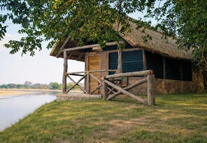 Eine rustikale Holzhütte mit einem Reetdach und einer Veranda.