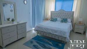 Une chambre à coucher avec un grand lit, des tables de chevet, une commode et un miroir.