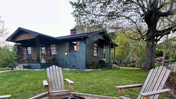 A house with a deck, outdoor seating, and a fire pit surrounded by flowers.