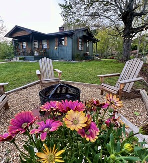 A house with a deck, outdoor seating, and a fire pit surrounded by flowers. - Misty Mountain Cozy & Stylish 2BR Cabin w/ Fire Pit near River & Attractions (Franklin)