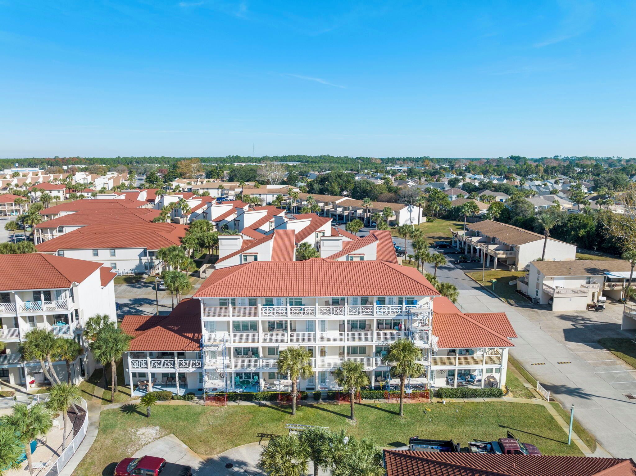 A multi-story hotel with a red-tiled roof, multiple balconies, and a pool area.