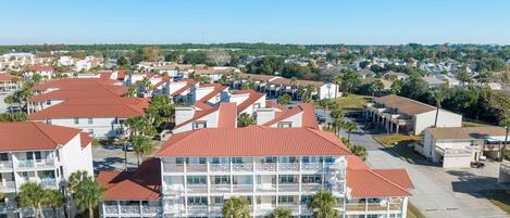 A multi-story hotel with a red-tiled roof, multiple balconies, and a pool area.