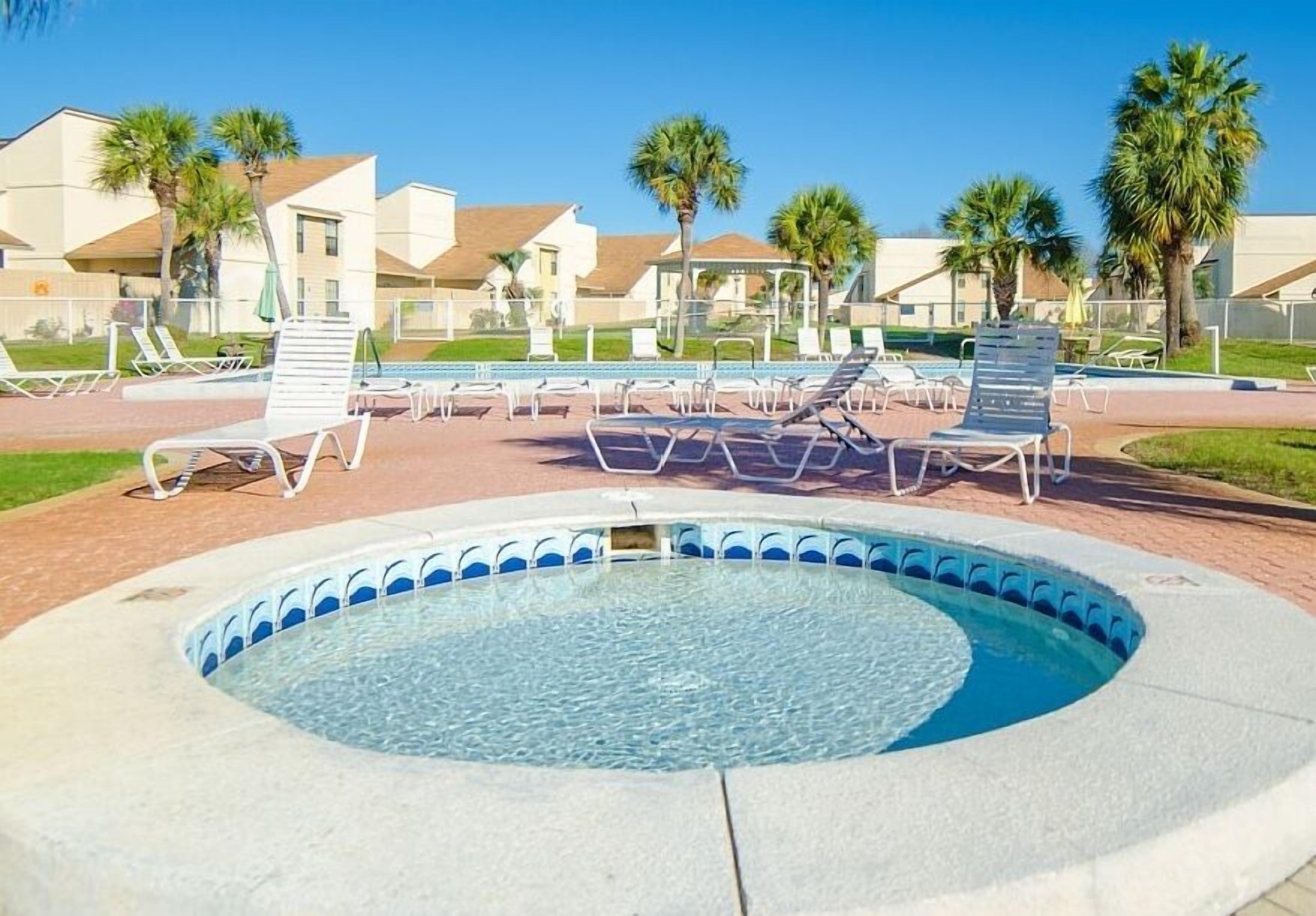 A swimming pool with lounge chairs and palm trees in the background.