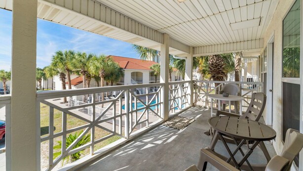 A covered outdoor area with a pool, white railings, and seating.
