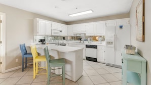 A kitchen with white cabinets, a central island, a microwave, a refrigerator, and a dishwasher.