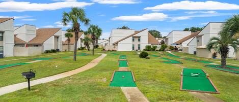 Un parcours de mini-golf entouré d’immeubles résidentiels, avec un ciel dégagé.