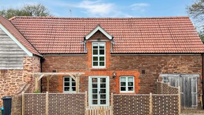 Een gebouw van baksteen met een rode pannendak, een houten poort en een stenen muur.