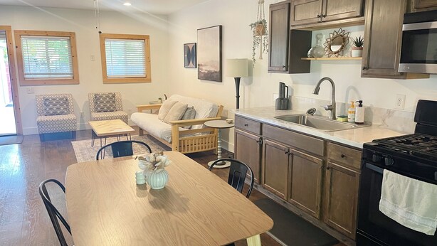 Una cocina moderna con armarios de madera, una estufa negra y un comedor con mesa y sillas de madera.