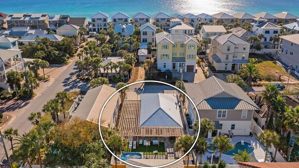 An aerial view of a coastal residential area with houses, a swimming pool, and a clear view of the ocean. - A Wave From It All - Beach Cottage with Private Pool & Outdoor Area (Miramar Beach)