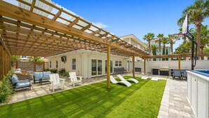 A covered patio with a pool, outdoor seating, and a well-maintained lawn. - A Wave From It All - Beach Cottage with Private Pool & Outdoor Area (Miramar Beach)