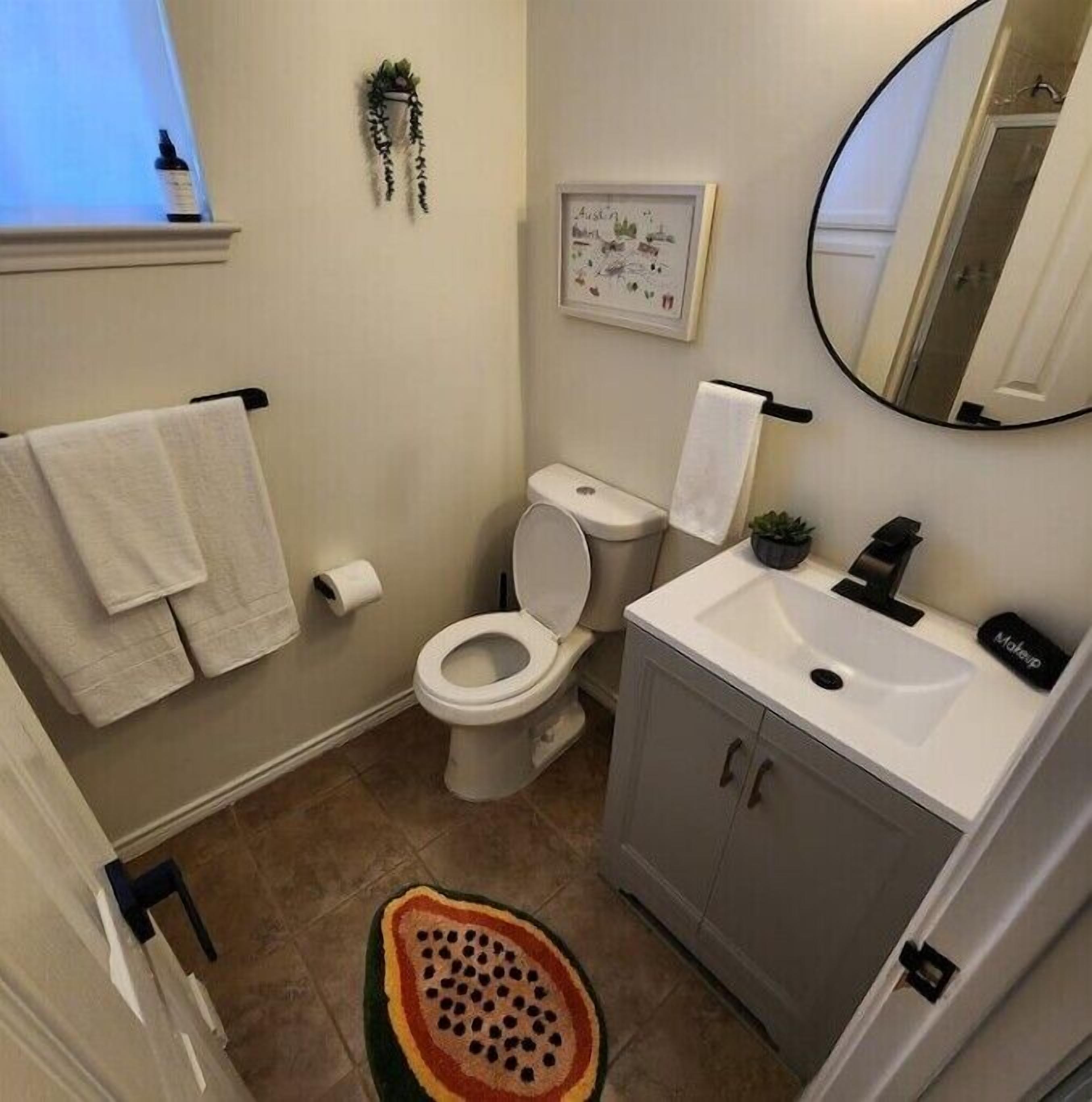 A bathroom with a toilet, sink, and a mirror.