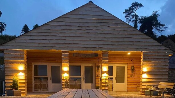 Une cabane en bois avec une table de pique-nique devant, entourée de gravier.