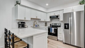 Una cocina moderna con armarios blancos, electrodomésticos de acero inoxidable y una isla central.