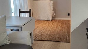 Een compacte, moderne kamer met een bed, een klein tafeltje en een stoel.