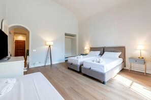 Una habitación de hotel con dos camas, un escritorio, un televisor y un espejo.