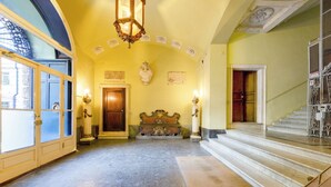 A grand hallway with a marble floor, a wooden door, a bench, and a staircase. - Nobel - Historic Center, Genova, Italy (Genova)
