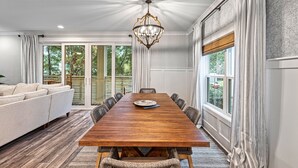Een eetkamer met een houten tafel, stoelen, een kroonluchter en een bank.