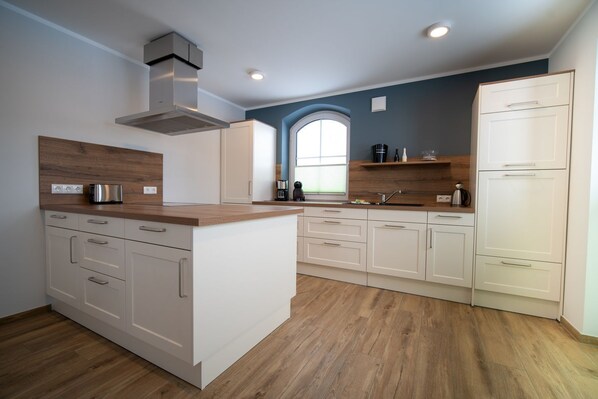 Una cocina moderna con armarios blancos, encimera de madera y una isla central.