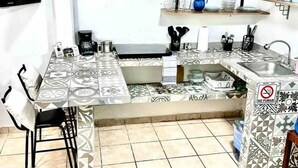 A compact kitchen with a tiled backsplash, a built-in sink, and a coffee maker. - Loft in the Heart of La Paz. 5 Blocks to Malecon Street (La Paz)