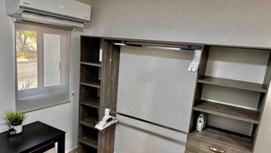 A compact room with built-in shelving, a small table with a plant, and an air conditioning unit. - Loft in the Heart of La Paz. 5 Blocks to Malecon Street (La Paz)