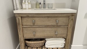 A wooden vanity with a white countertop, three drawers, and a wicker basket below.