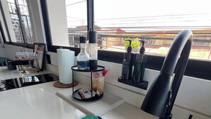 A modern kitchen with a stainless steel sink, a coffee machine, and a window with a view of the cityscape. - Oasis Loft 5min from SJO airport cozy and comfy fully equipment  down town A/C (Alajuela)