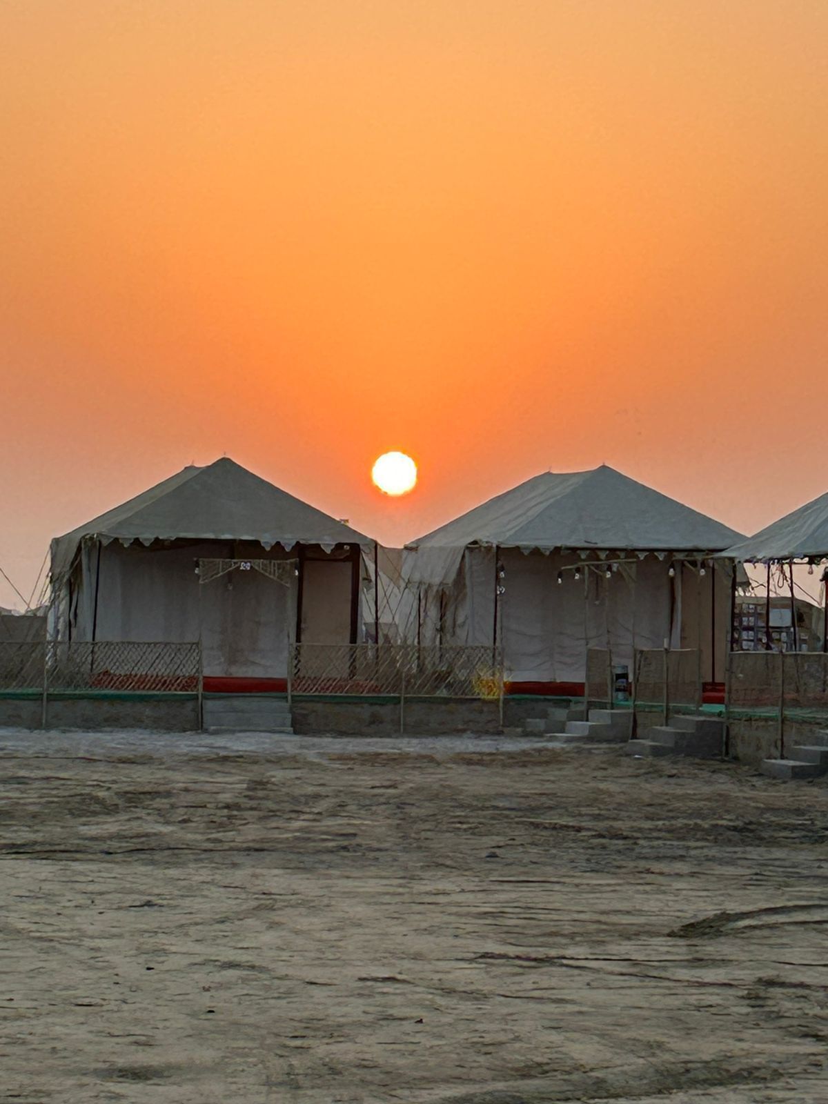 A desert landscape with two tents and a clear sky.
