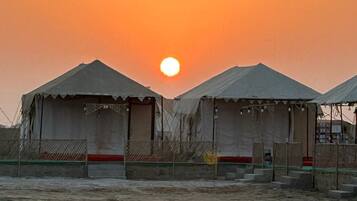 A desert landscape with two tents and a clear sky.