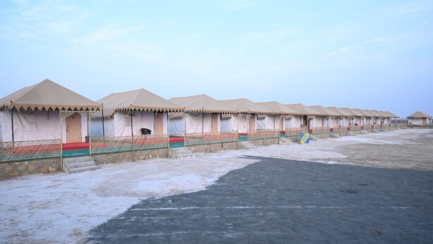 A row of tents with a paved walkway in between. - DESERT INN CAMP (Bhuj)