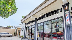 A barbershop with large windows and a car parked outside.