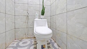 A bathroom with a toilet, a cactus, and a bottle of hand soap.