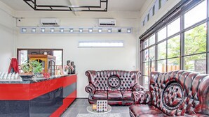 A reception area with a red counter, a leather sofa, and a large window with a view of greenery.