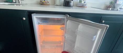Une cuisine équipée d’un réfrigérateur encastré, d’un évier et d’une machine à café.