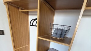 Una estantería de madera con varios compartimentos, incluyendo una cesta de alambre y una toalla doblada.